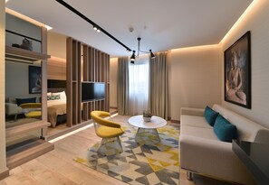 Un salon moderne avec un canapé, un fauteuil et une table basse, un téléviseur à écran plat et une grande statue de Bouddha accrochée au mur.