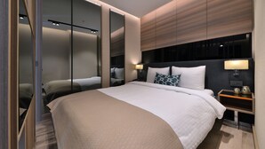 Una habitación de hotel moderna con una cama grande, una mesita de noche con lámpara y un armario con puertas correderas.