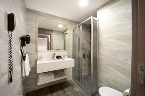 A modern bathroom with a glass-enclosed shower, a white sink, and a hairdryer mounted on the wall. - Nish Palace Exclusive Suites (Istanbul)