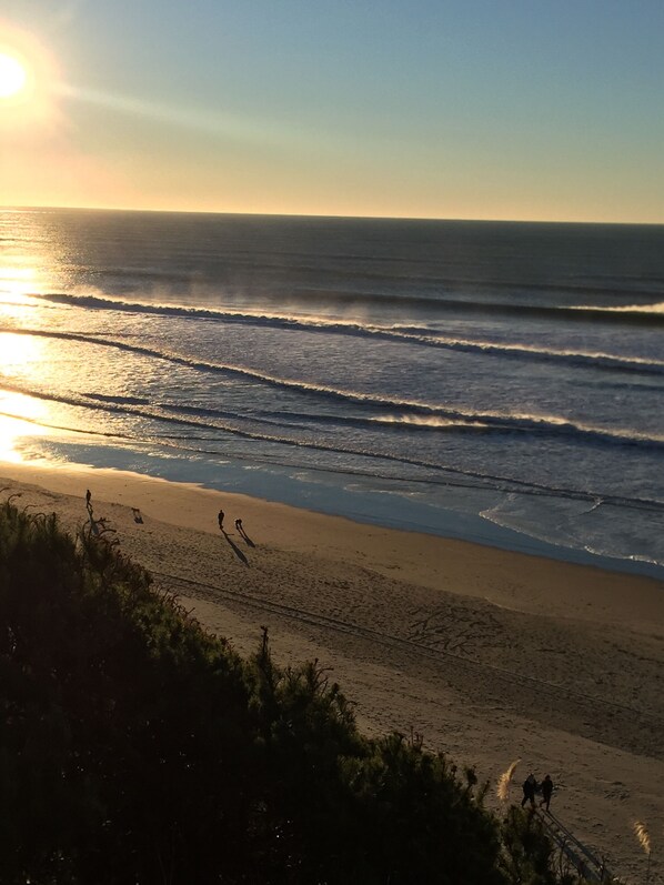 Una playa con olas y gente caminando.