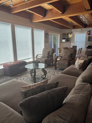 A living room with a high ceiling, patterned chairs, a glass coffee table, and a sofa.