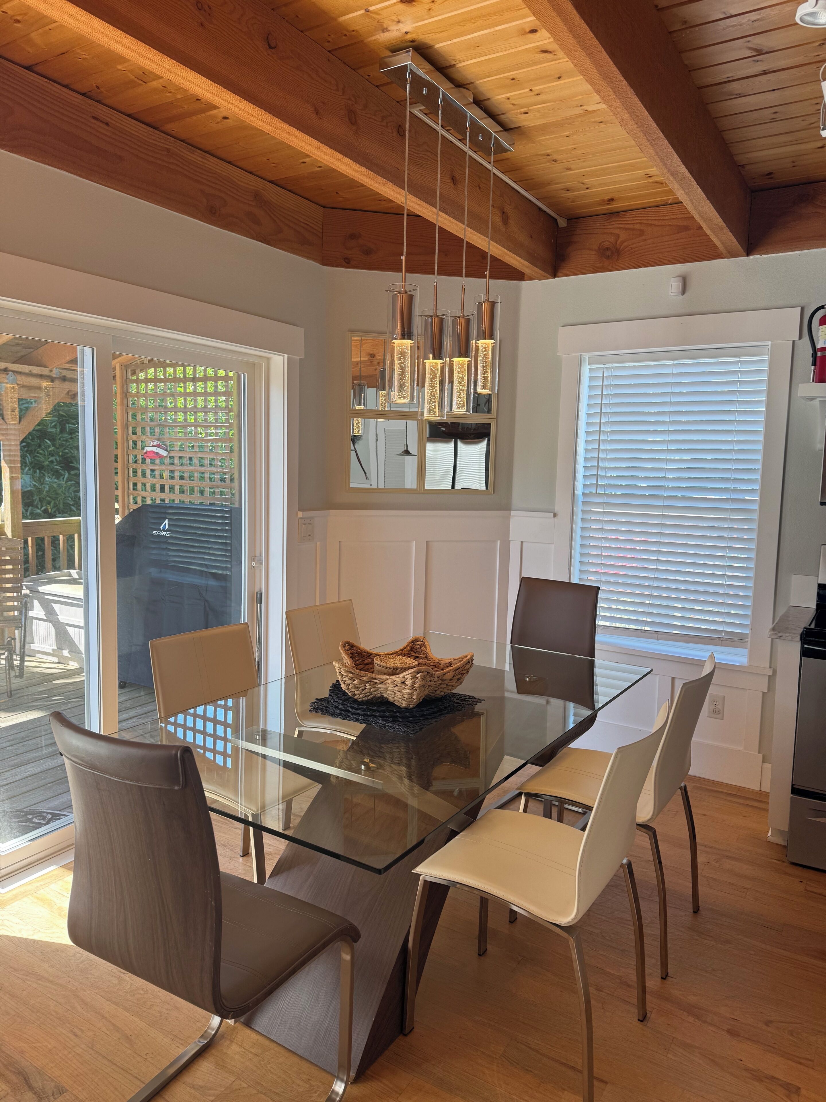 A dining area with a glass table, chairs, and a woven basket centerpiece.