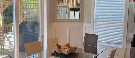 A dining area with a glass table, chairs, and a woven basket centerpiece.
