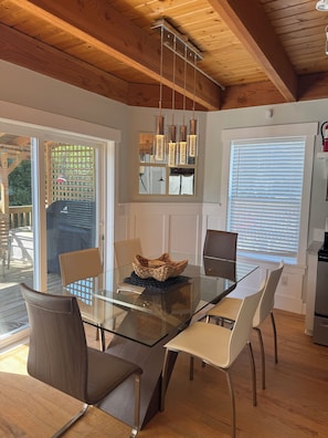 A dining area with a glass table, chairs, and a woven basket centerpiece.