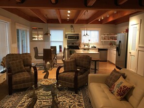 A spacious living room with patterned sofas, a coffee table, and a dining area with chairs and a table.