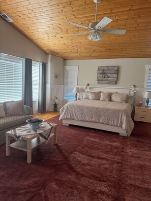 A bedroom with a bed, bedside tables, a ceiling fan, and a window with curtains.