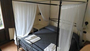 A single bed with a canopy, a bedside table, and a wall-mounted lamp.