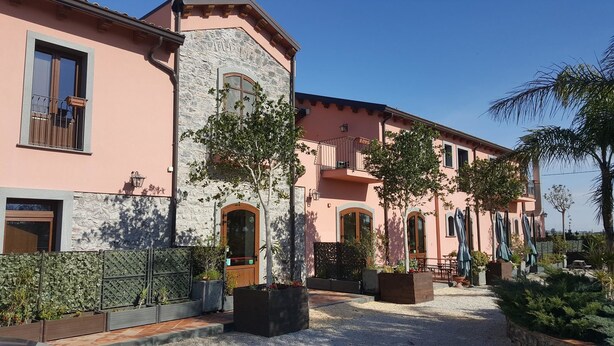 A building with a stone facade, multiple balconies, and a courtyard with potted plants and outdoor seating.