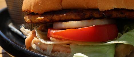 A sandwich with a bun, lettuce, tomato, and a meat patty, accompanied by a side of French fries.