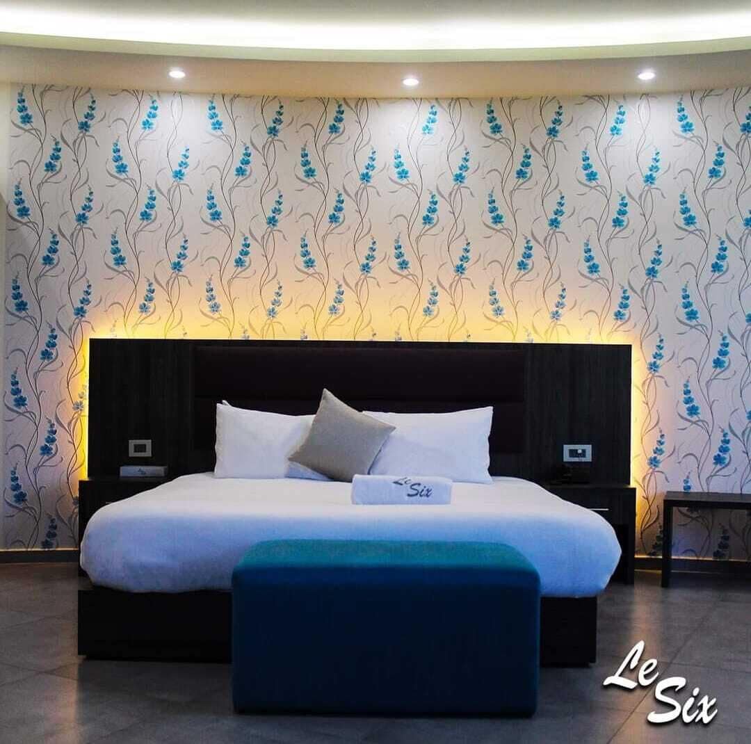 A modern bedroom with a large bed, a headboard, and a nightstand.