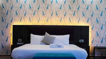 A modern bedroom with a large bed, a headboard, and a nightstand.