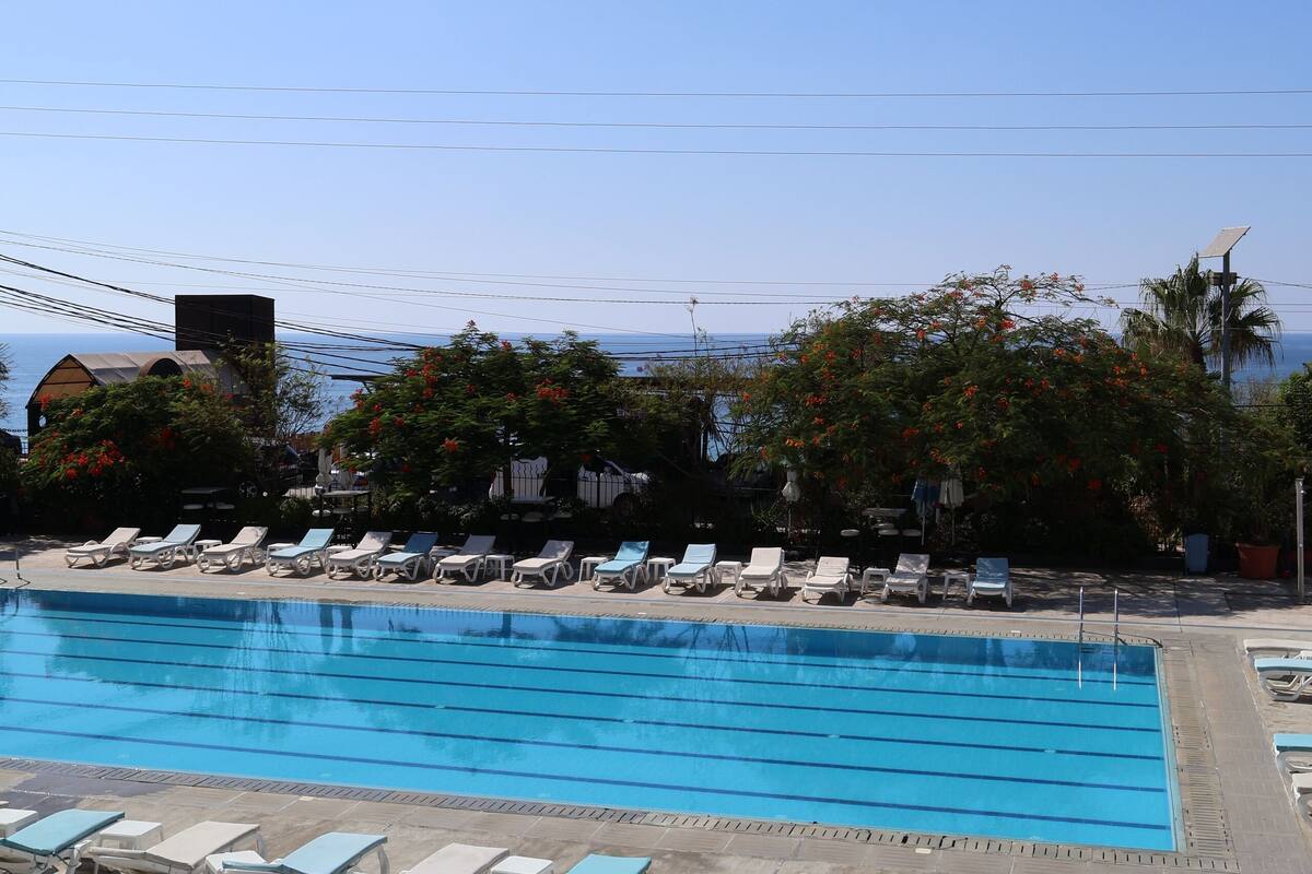 A swimming pool with lounge chairs and a view of the ocean.