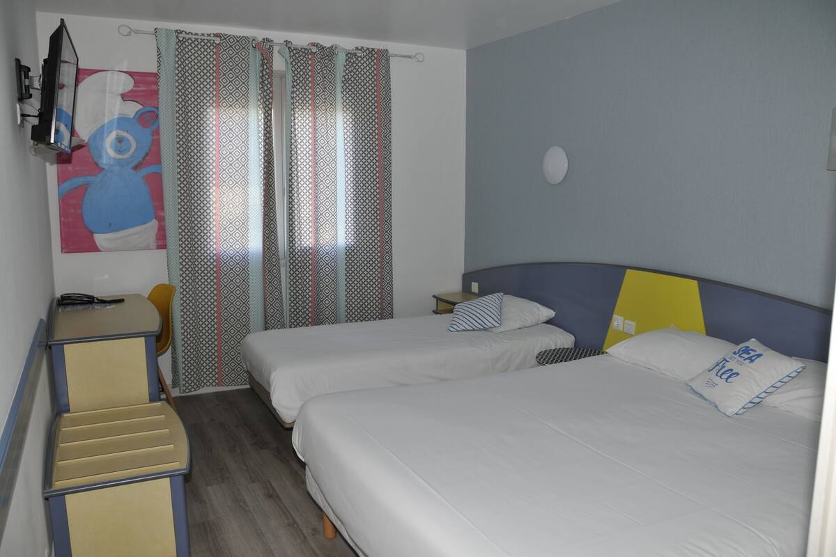 Een hotelkamer met twee bedden, een bureau en een stoel.