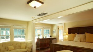 A spacious living room with a large sofa, a smaller armchair, and a wooden bed with a headboard. - Smithfield Inn (Smithfield)