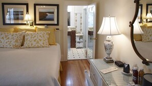 A hotel room with a bed, two bedside lamps, a mirror, a dresser, and a small table with a lamp. - Smithfield Inn (Smithfield)