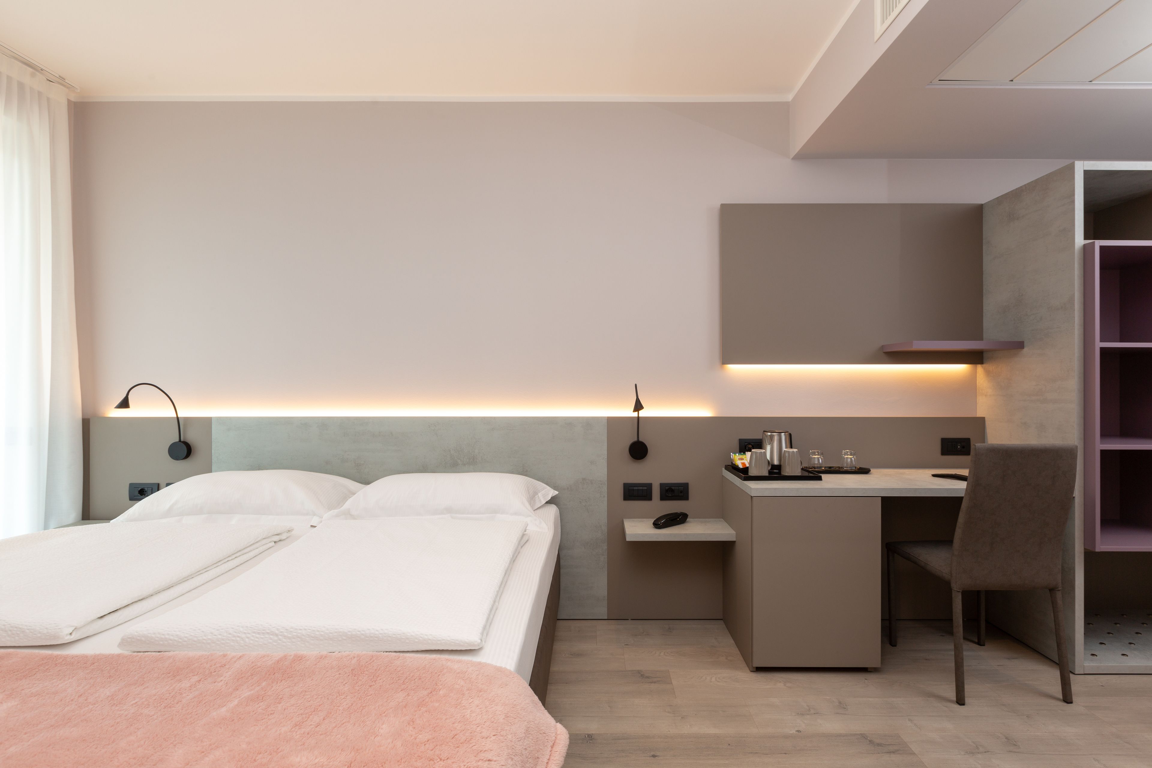 Una moderna camera d'hotel con un letto, una scrivania e una sedia.