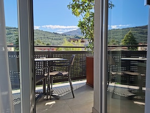 A balcony with a table and chairs, overlooking a mountainous landscape. - Garda Life (Riva del Garda)