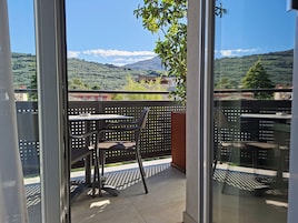 Un balcón con mesa y sillas, con vistas a un paisaje montañoso.