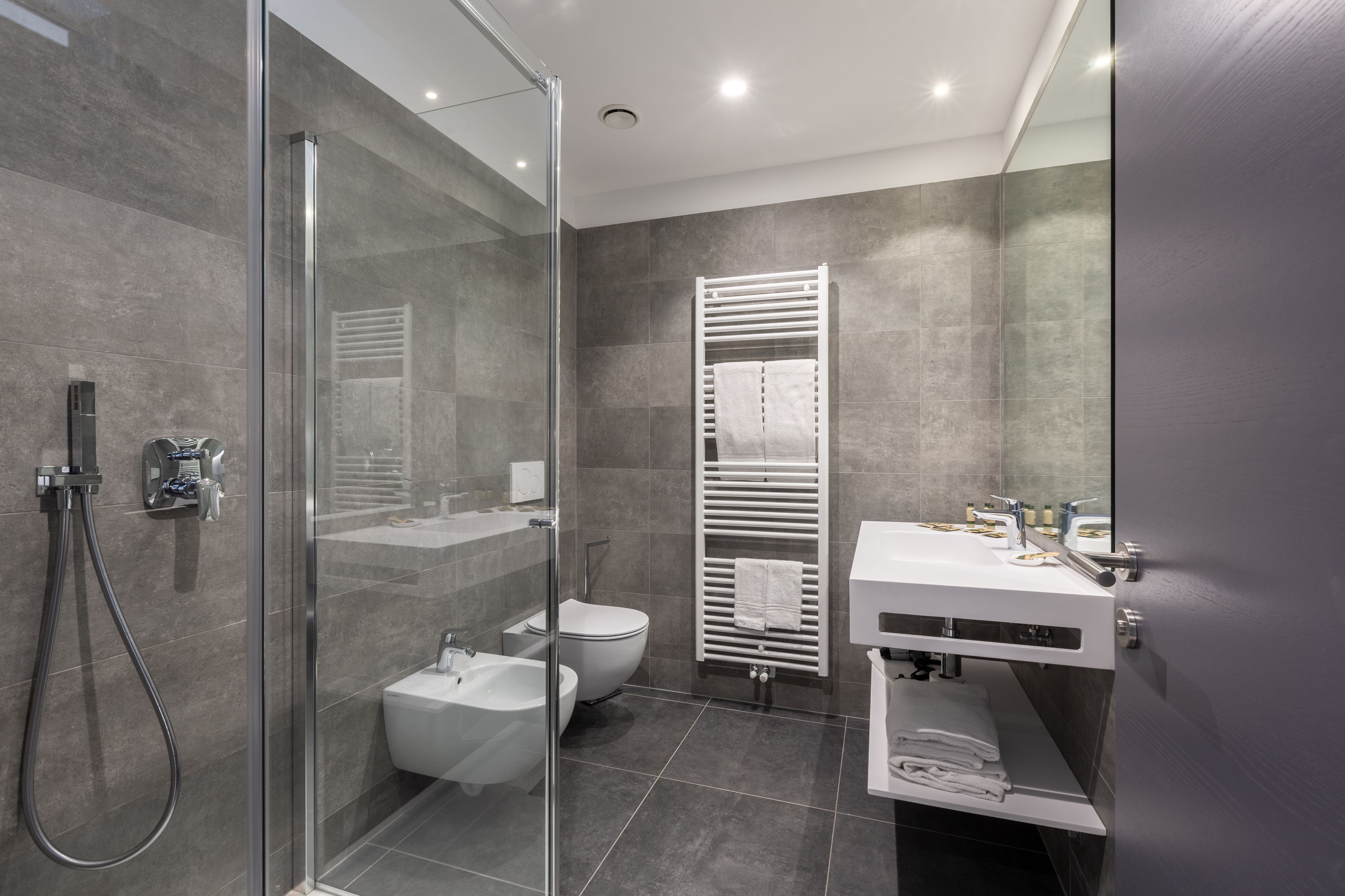 Un baño moderno con ducha envuelta en vidrio, un lavabo blanco y un inodoro.