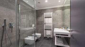 A modern bathroom with a glass-enclosed shower, a white sink, and a toilet.