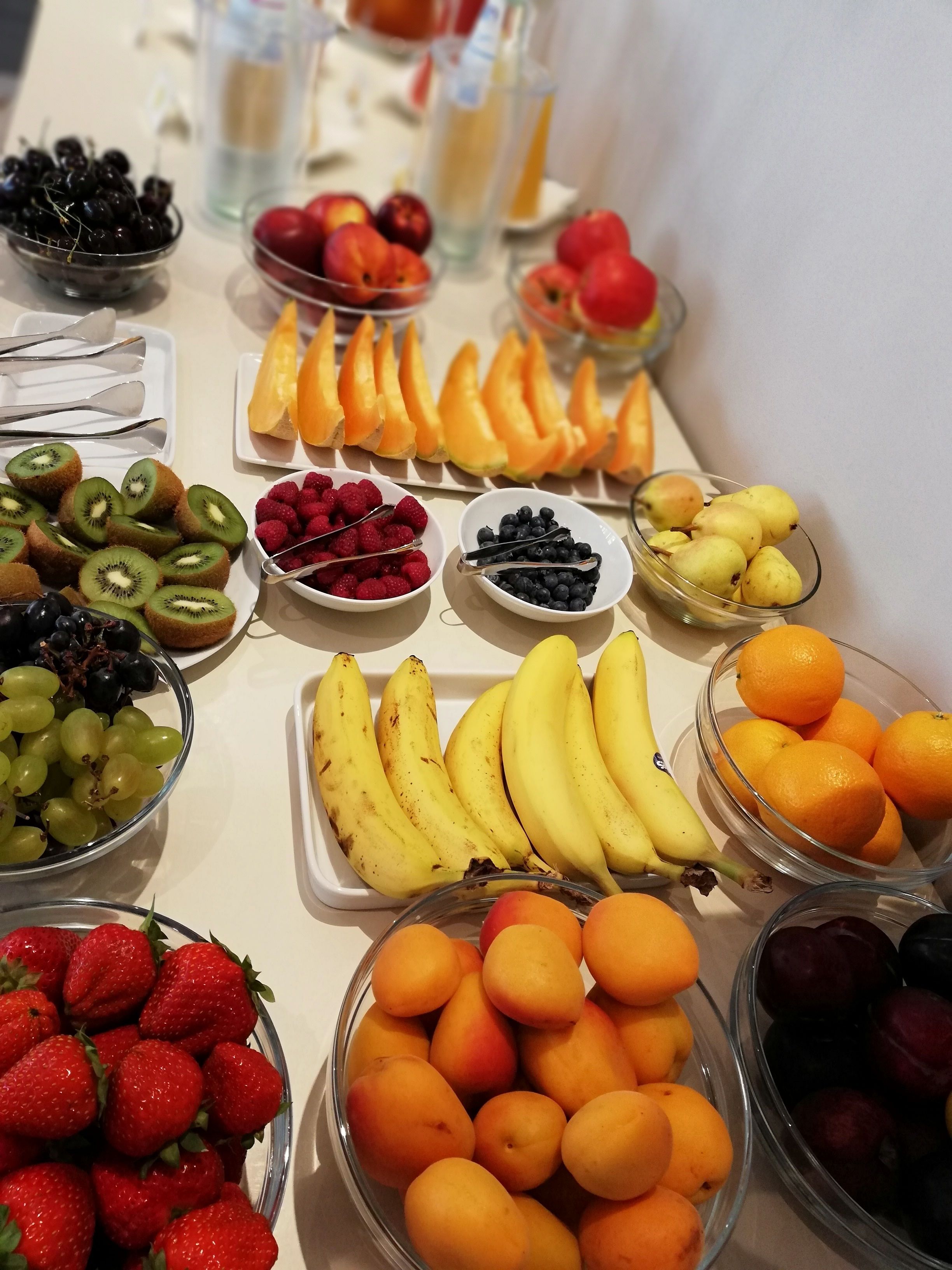 A table with various fruits and a glass of water.