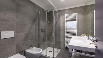Un baño moderno con ducha de vidrio, lavamanos blanco y bidé.