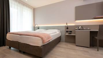 Ein modernes Hotelzimmer mit einem Bett, einem Schreibtisch und einem Stuhl.