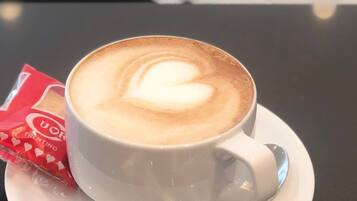 A cup of coffee with a heart-shaped latte art on a white saucer.