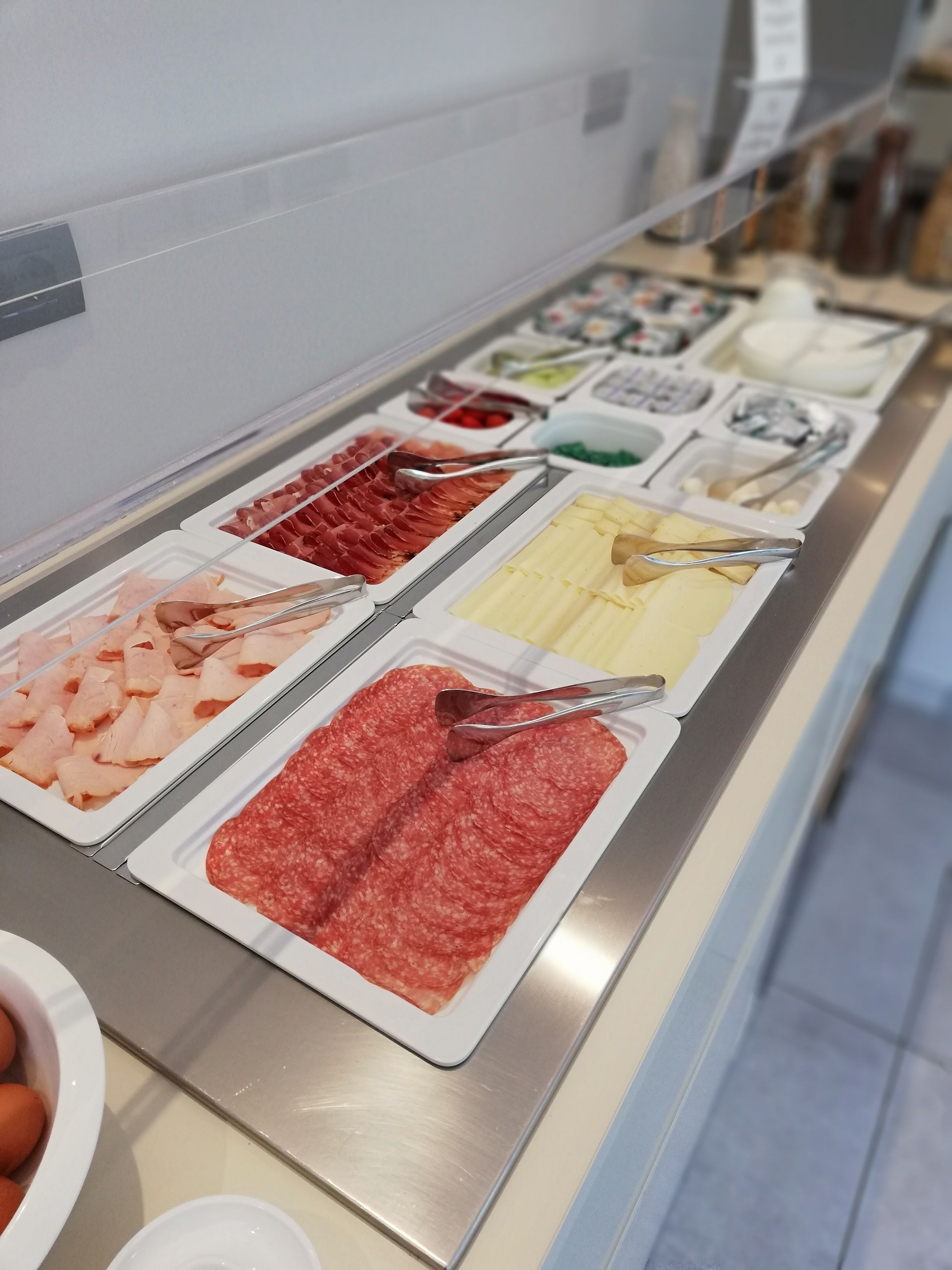 Un bufé con diversas opciones de comida, incluyendo carnes y quesos.