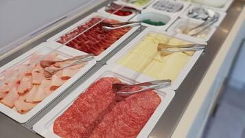 Un bufé con diversas opciones de comida, incluyendo carnes y quesos.