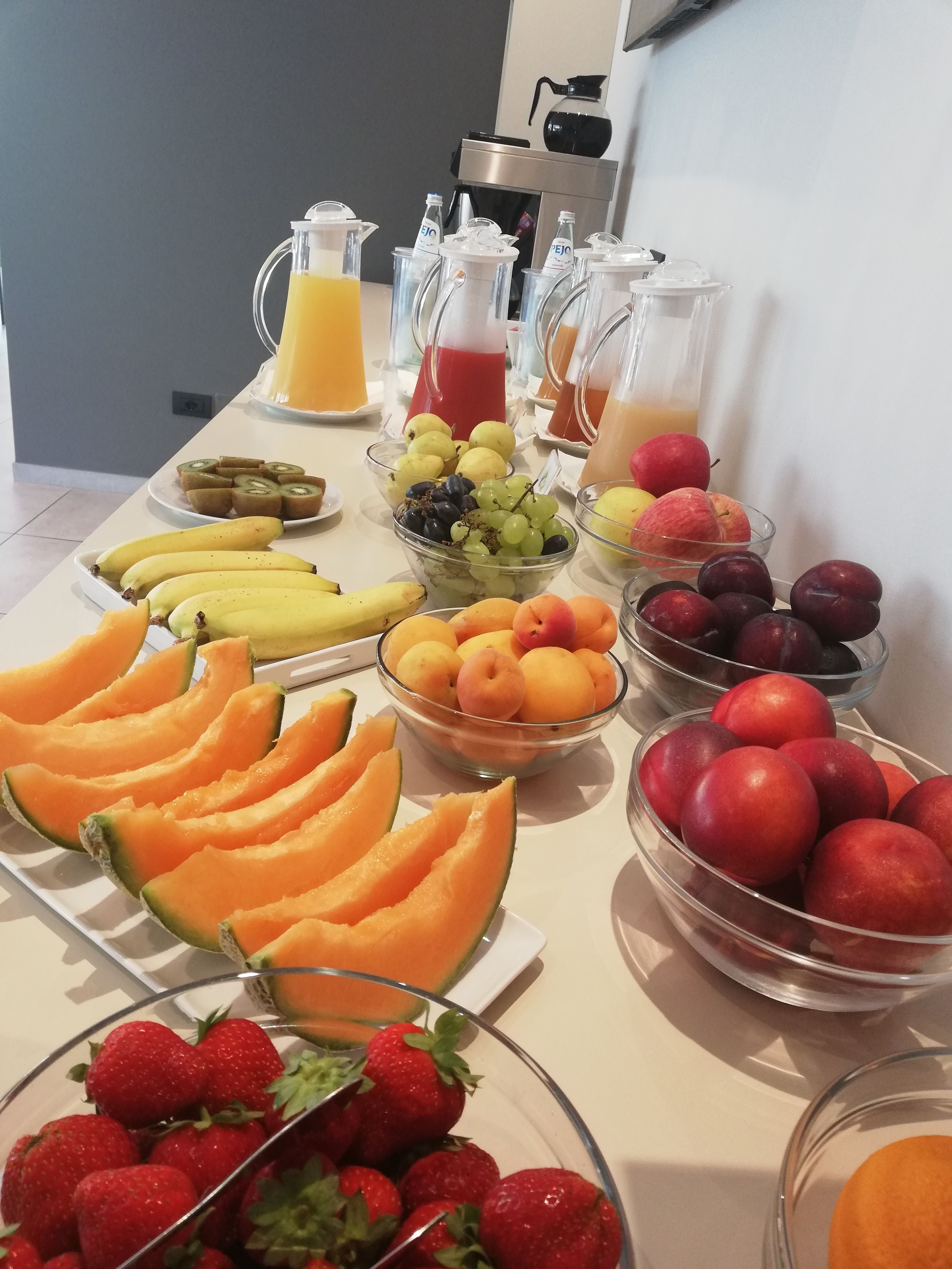 A buffet table with various fruits and beverages.