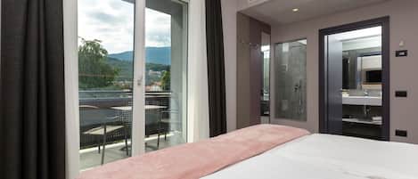 A hotel room with a bed, a sliding glass door to a balcony, and a shower area.