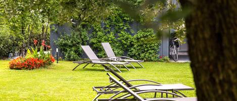 A garden area with lawn chairs and a bicycle.