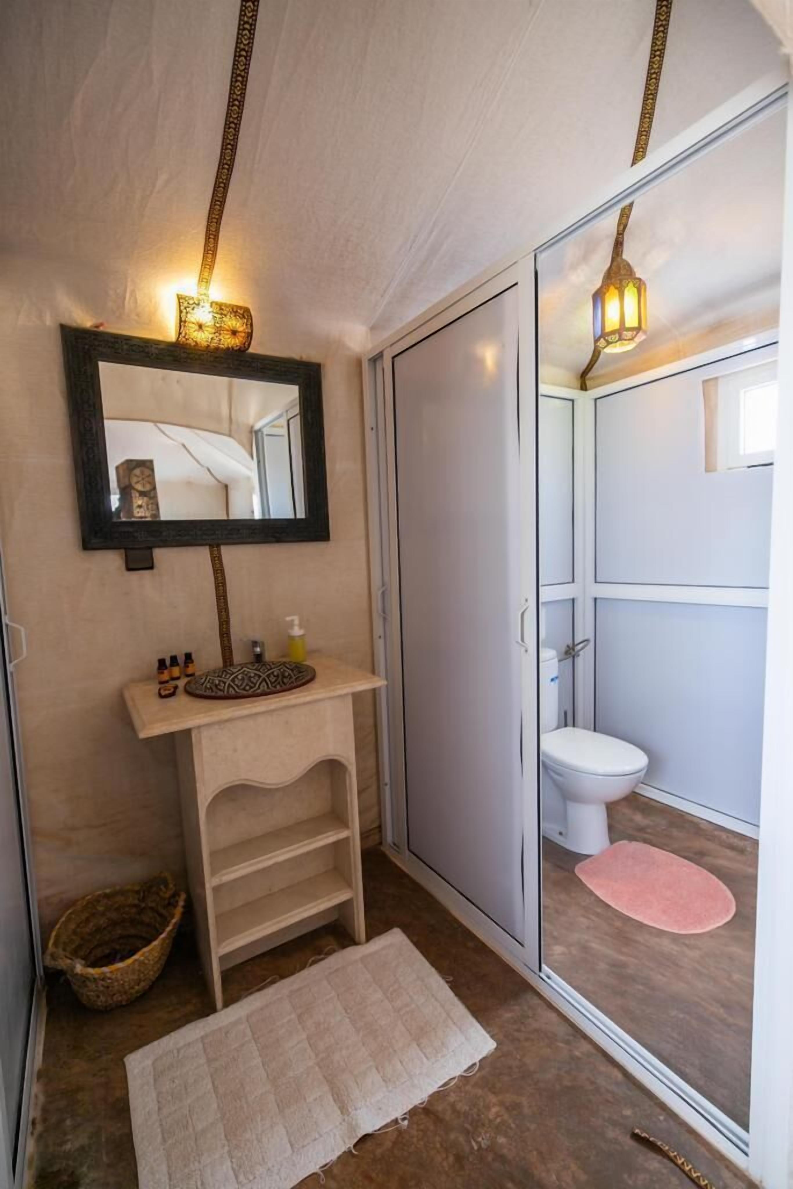 A bathroom with a wooden vanity, a mirror, a toilet, and a shower area.