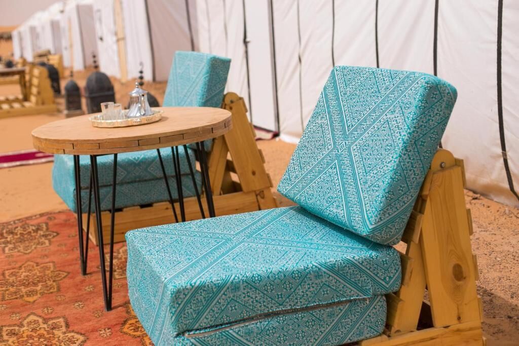 A seating area with a round wooden table and two blue patterned chairs.