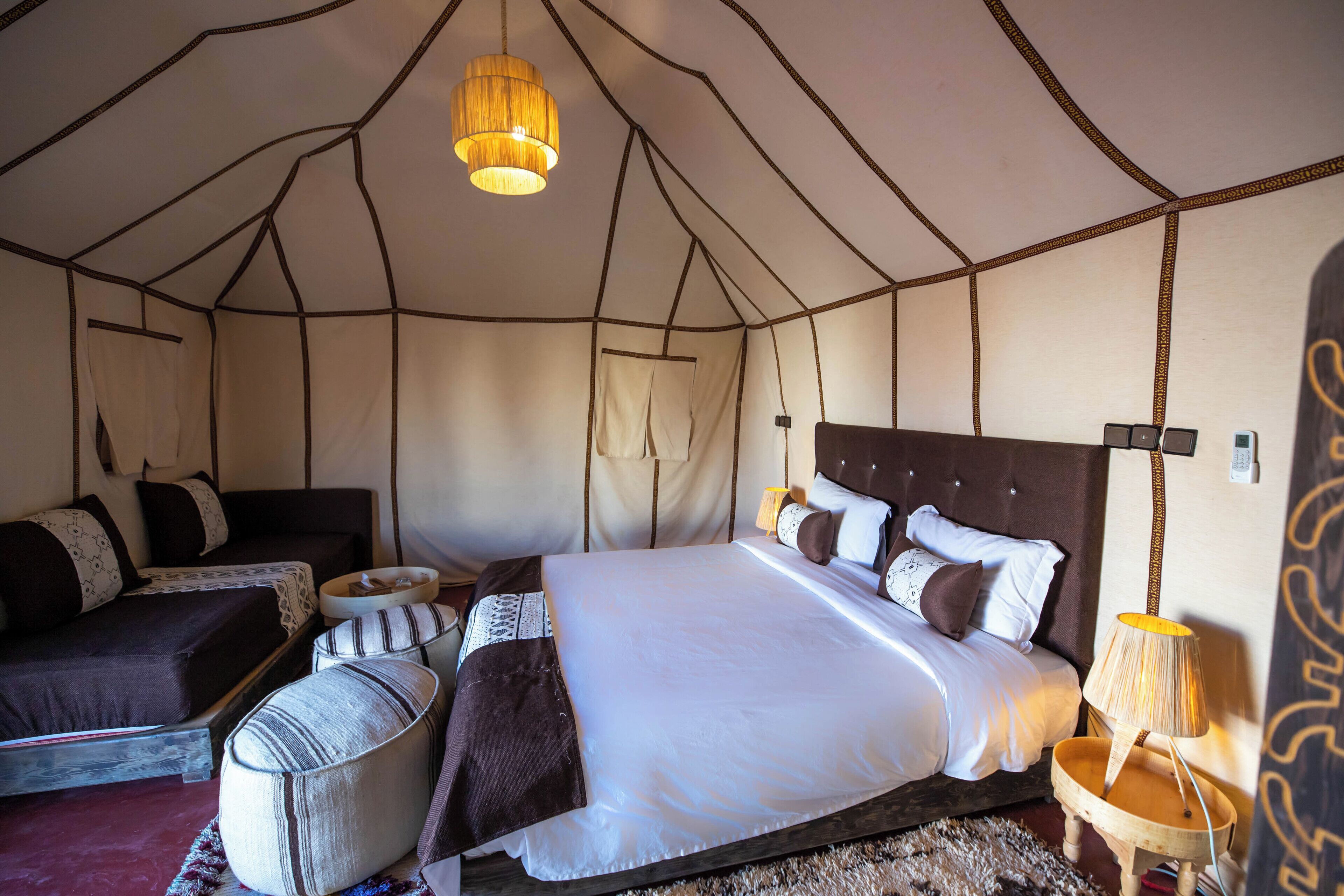 A tent-style room with a large bed, a sofa, and a small table.
