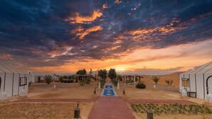 A desert landscape with a pathway leading to a building with a red roof. - DWO Golden Camp Merzouga (Taouz)