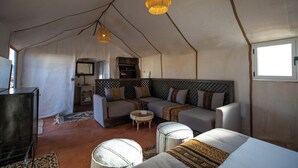 A tent-style room with a sofa, ottoman, and hanging light fixtures. - DWO Golden Camp Merzouga (Taouz)