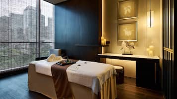 Relax in a serene space with a large window offering a view of the outdoors, a comfortable bed, and a cozy table with candles.