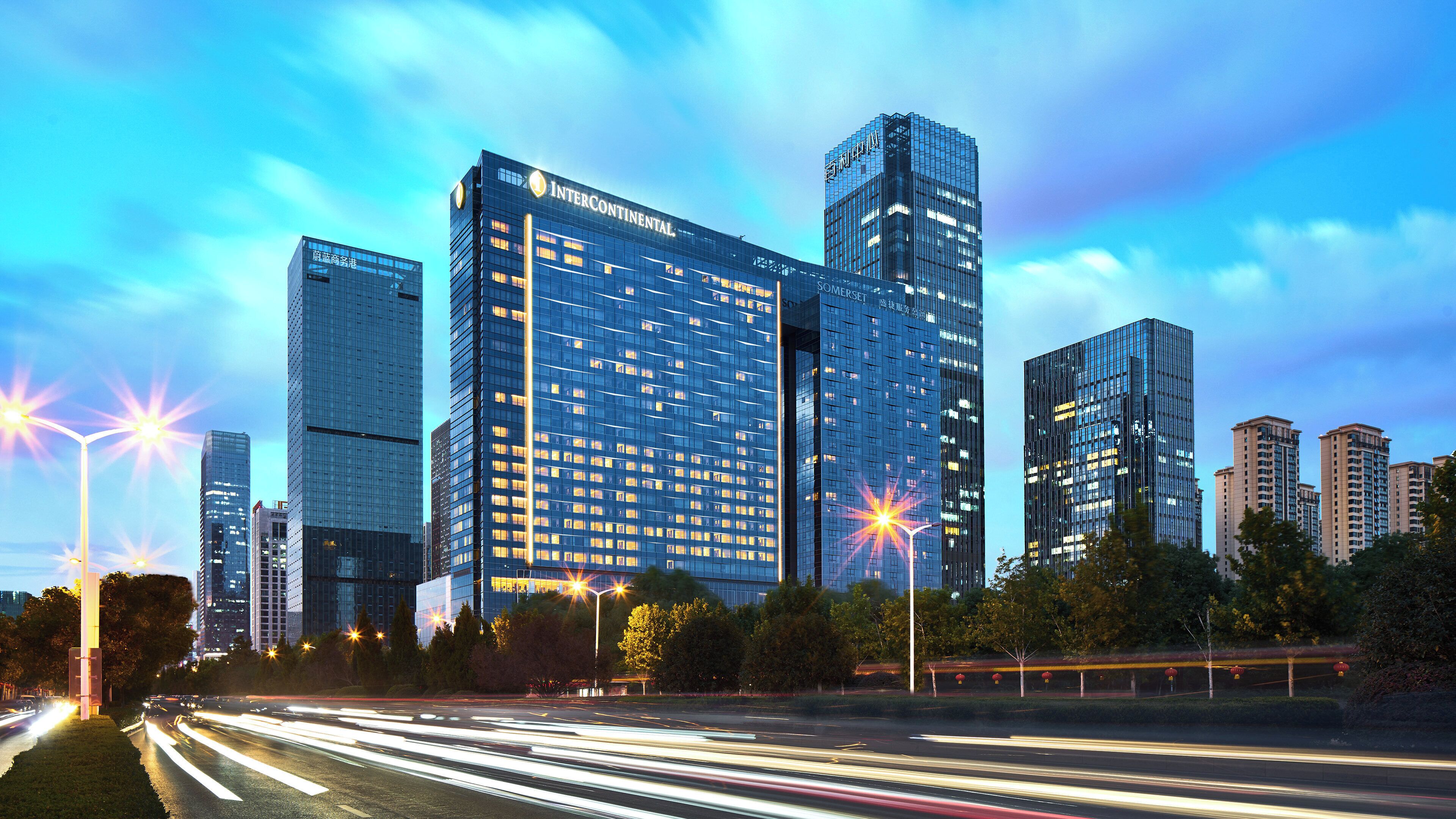 A modern high-rise building with a glass facade and illuminated windows.