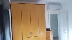 Une pièce comprenant une armoire en bois, une petite commode et un appareil de climatisation fixé au mur.
