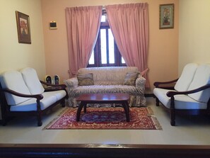 A living room with a sofa, two armchairs, a coffee table, and a patterned rug.