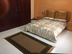 A bedroom with a bed, nightstands, a wardrobe, and a patterned rug.