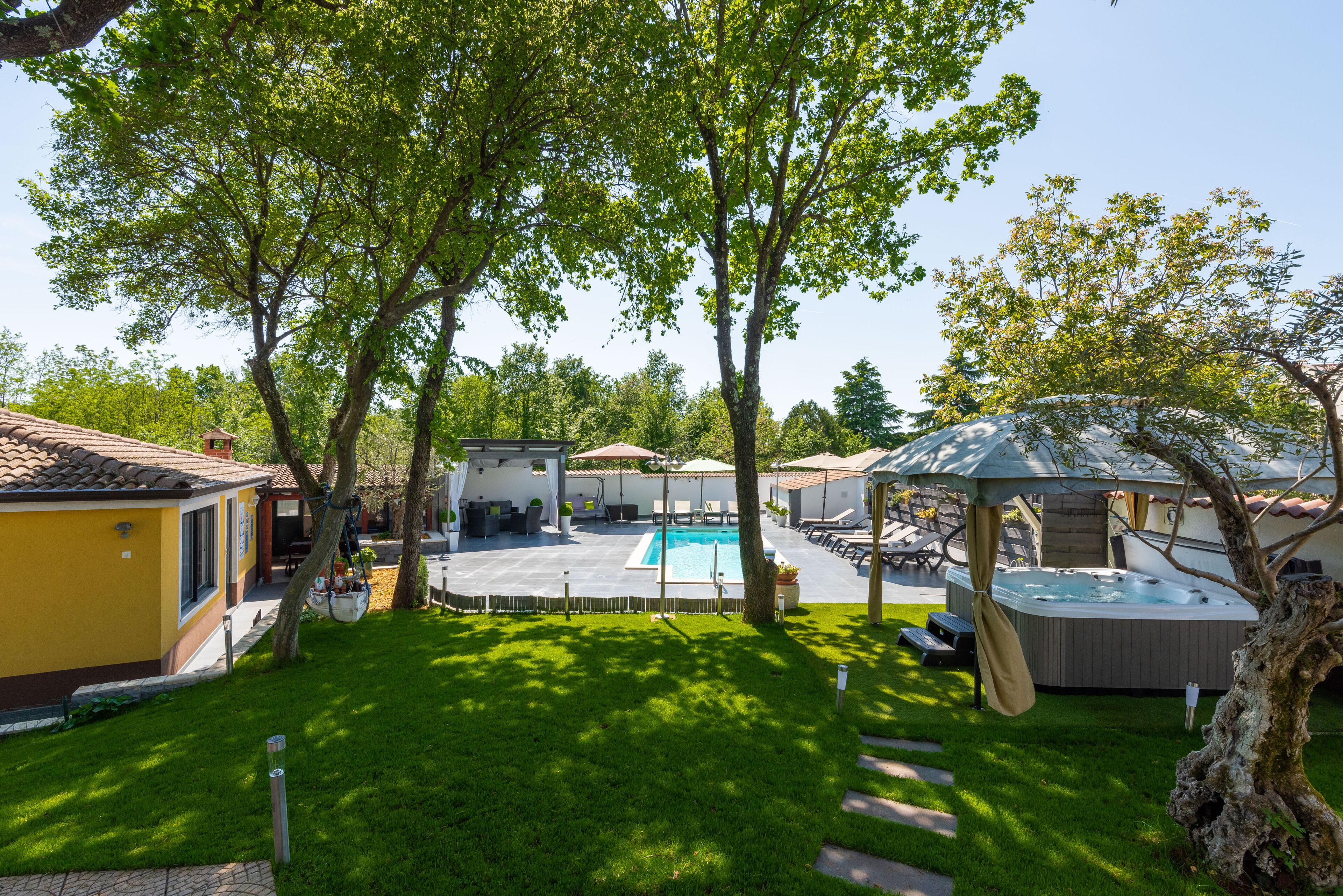 Un jardin avec une piscine, un jacuzzi et un espace salon abrité.
