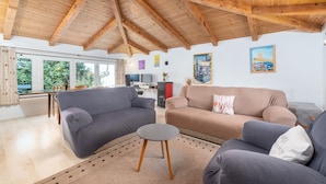 A spacious living room with wooden beams, a grey sofa, a beige sofa, and a small round table. - Felix Residence (Porec)