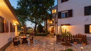 A courtyard with stone flooring, outdoor seating, potted plants, and a staircase leading to an upper level. - Felix Residence (Porec)