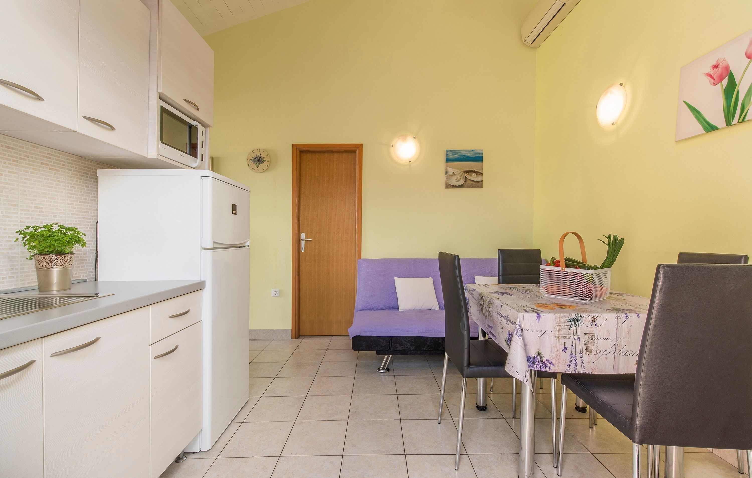 A compact kitchen with a microwave, refrigerator, and a potted plant.
