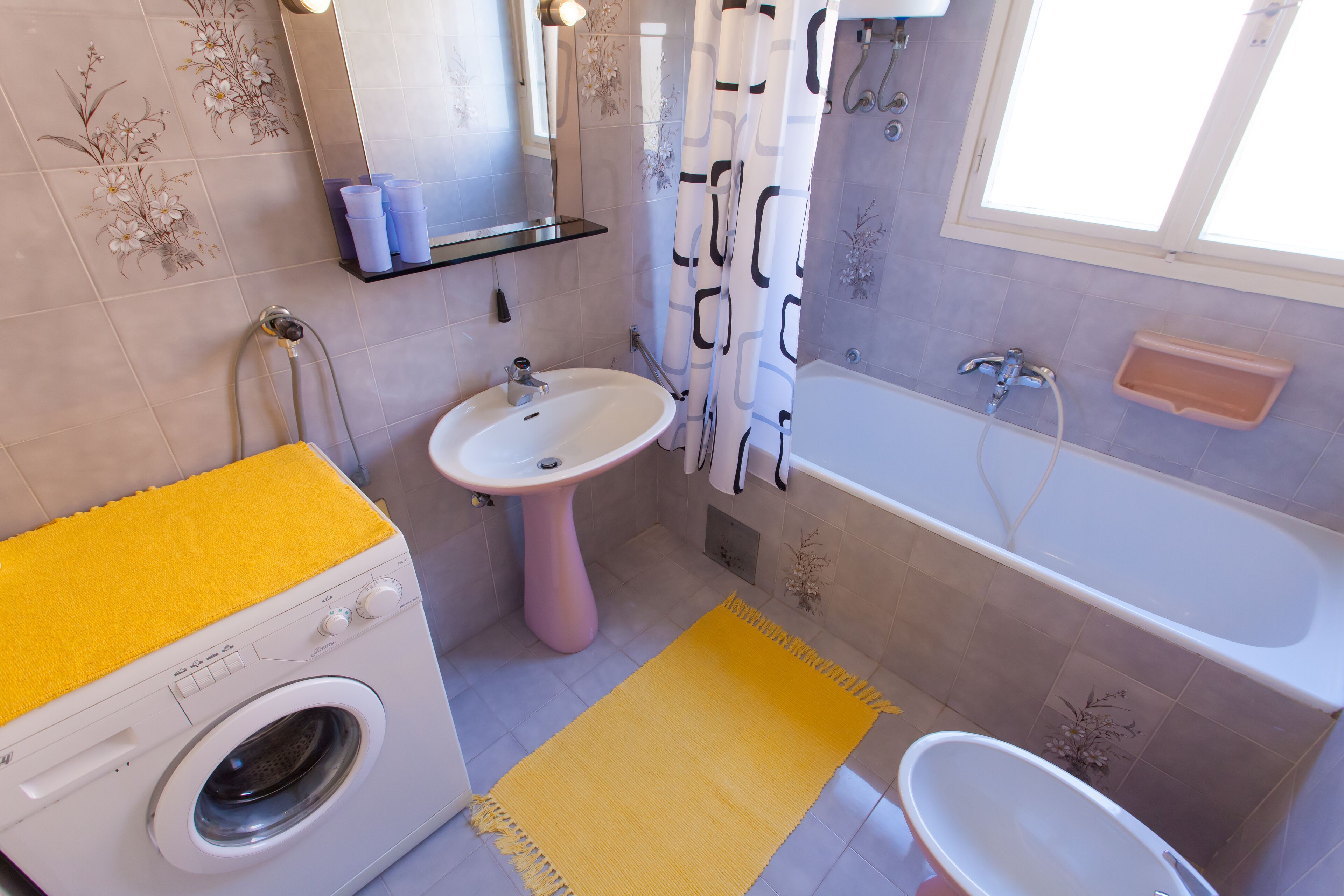 A bathroom with a washing machine, sink, and bathtub.