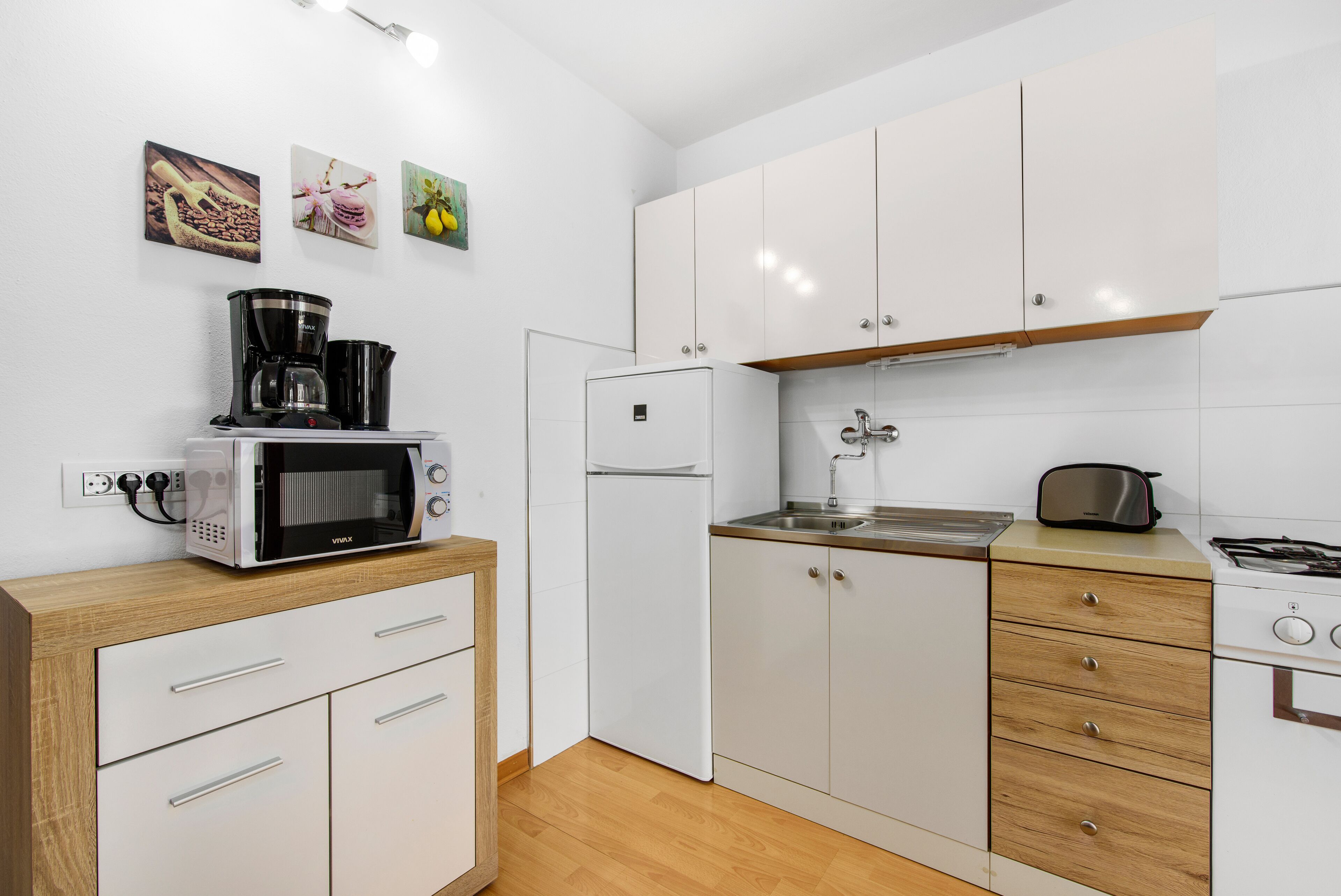 A modern kitchen with white cabinets, a microwave, a coffee maker, a refrigerator, and a stove.