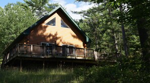 Eine Blockhütte mit Balkon, umgeben von Wald.